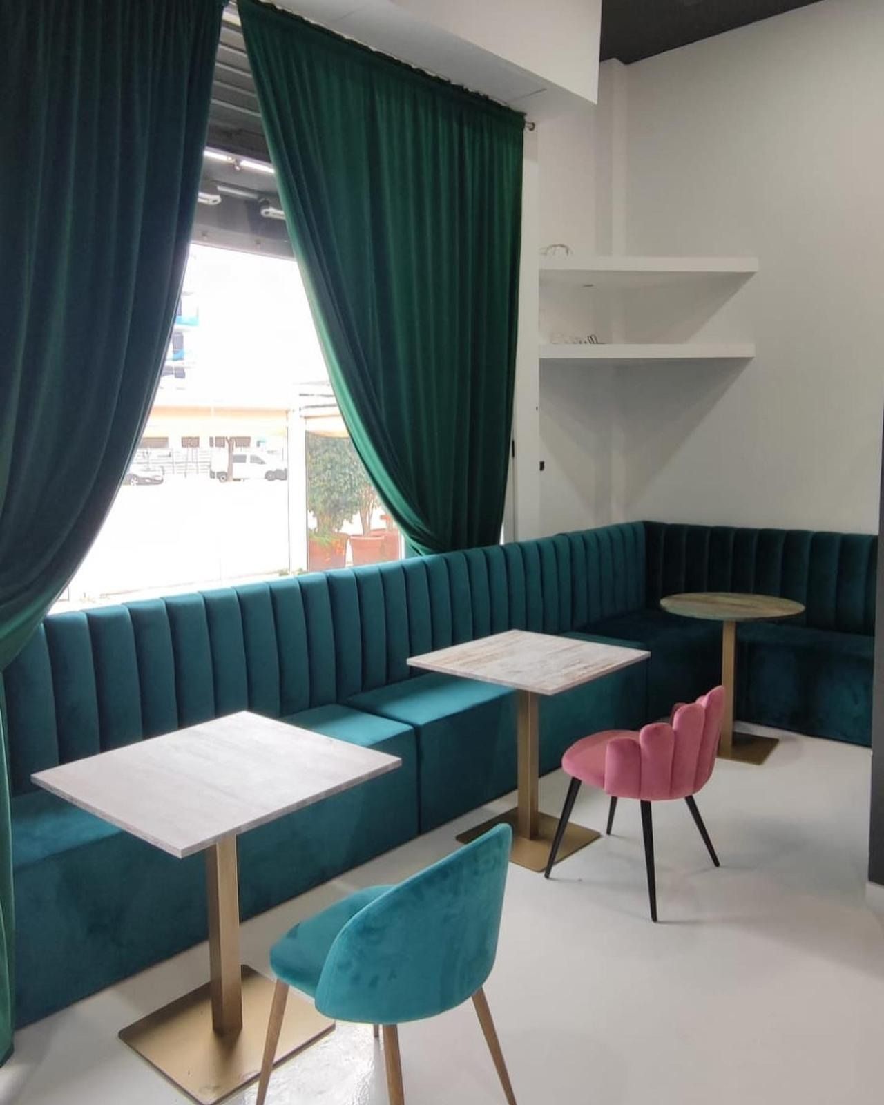 Un sofá largo y verde está colgado en una pared blanca.