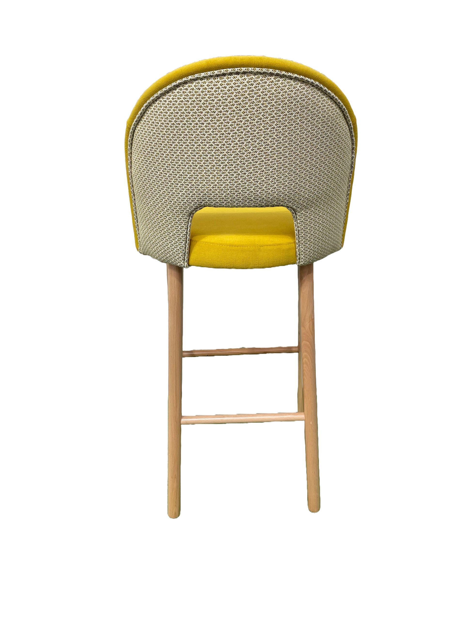 Un taburete de bar amarillo con patas de madera sobre un fondo blanco.