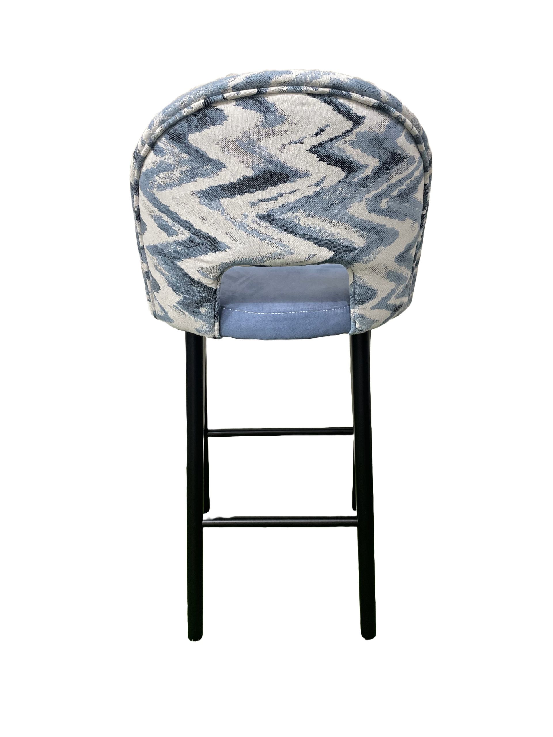 Un taburete de bar azul y blanco con un patrón de chevrones en la parte posterior.