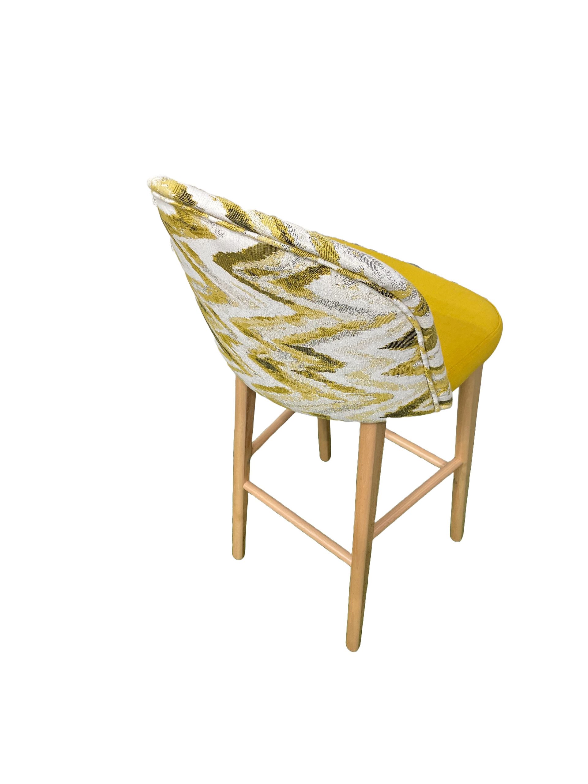 Un taburete de bar amarillo y blanco con patas de madera.