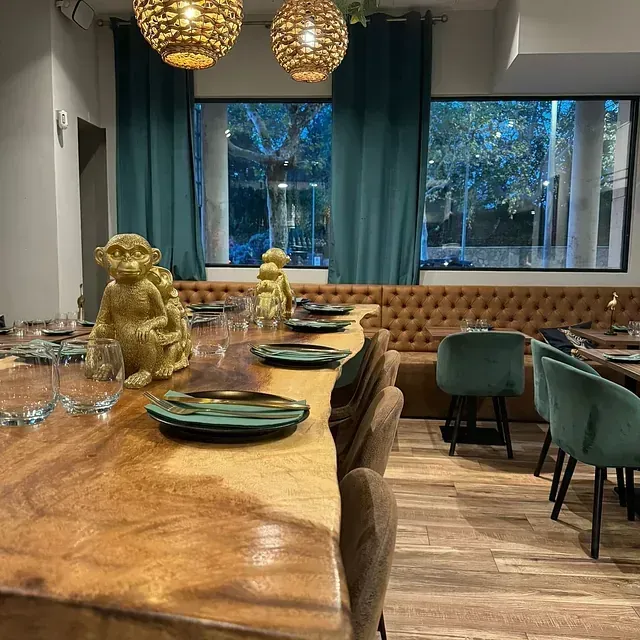 Un restaurante con una mesa larga con platos y vasos encima.