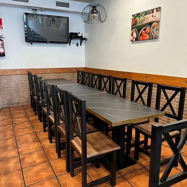 Un comedor con mesas y sillas y un televisor en la pared.