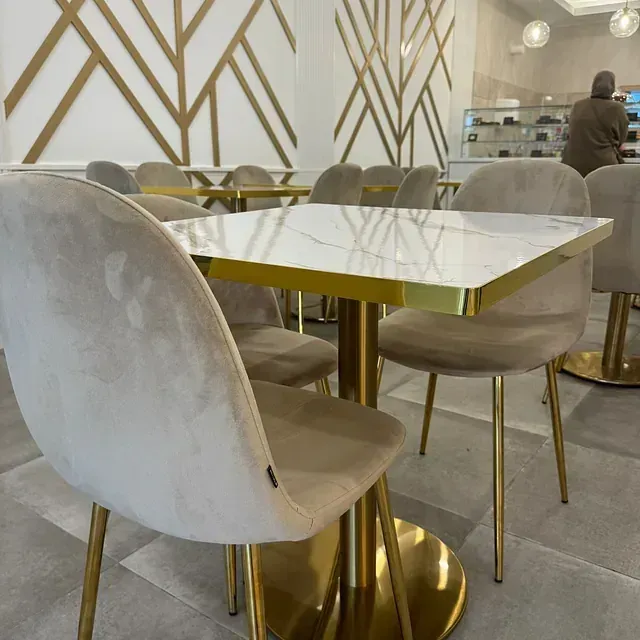Un restaurante con mesas y sillas con base dorada.