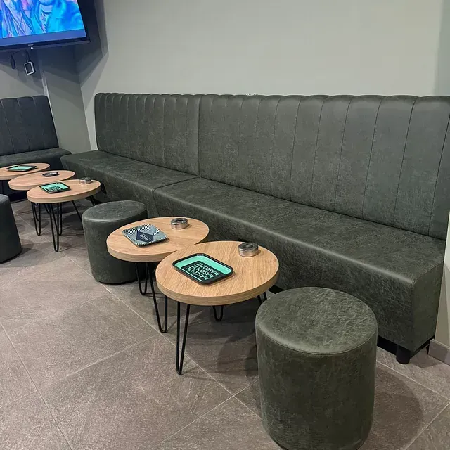 Una sala de estar con un sofá largo, mesas y otomanas.