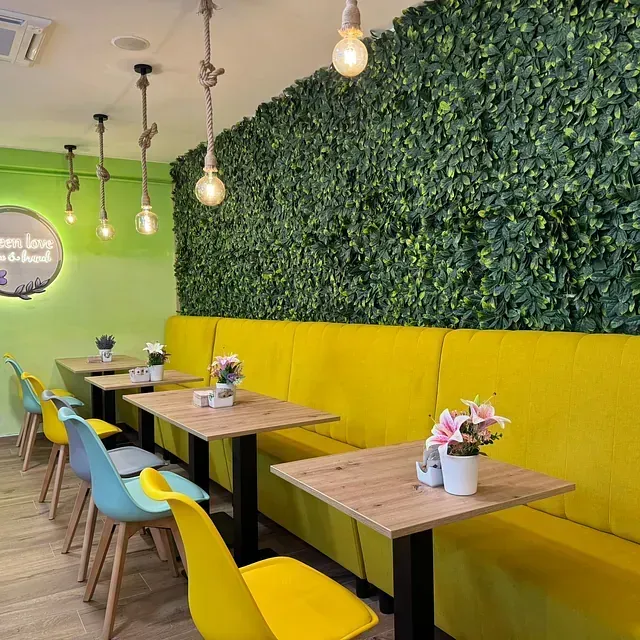 Un restaurante con mesas y sillas y una pared verde.