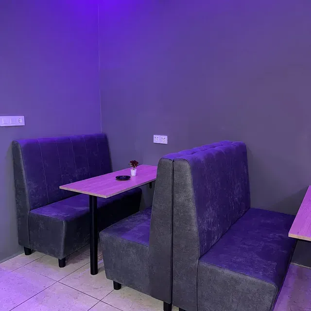Una luz violeta brilla sobre una habitación con una mesa y bancos.