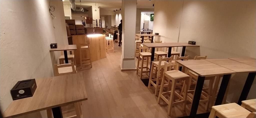 Un restaurante lleno de mesas y taburetes de madera.