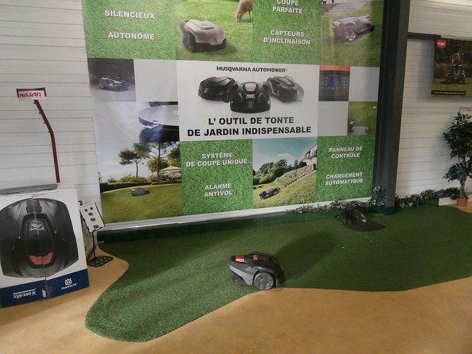 Robot tondeuse à côté d'une affiche de la marque Husqvarna®