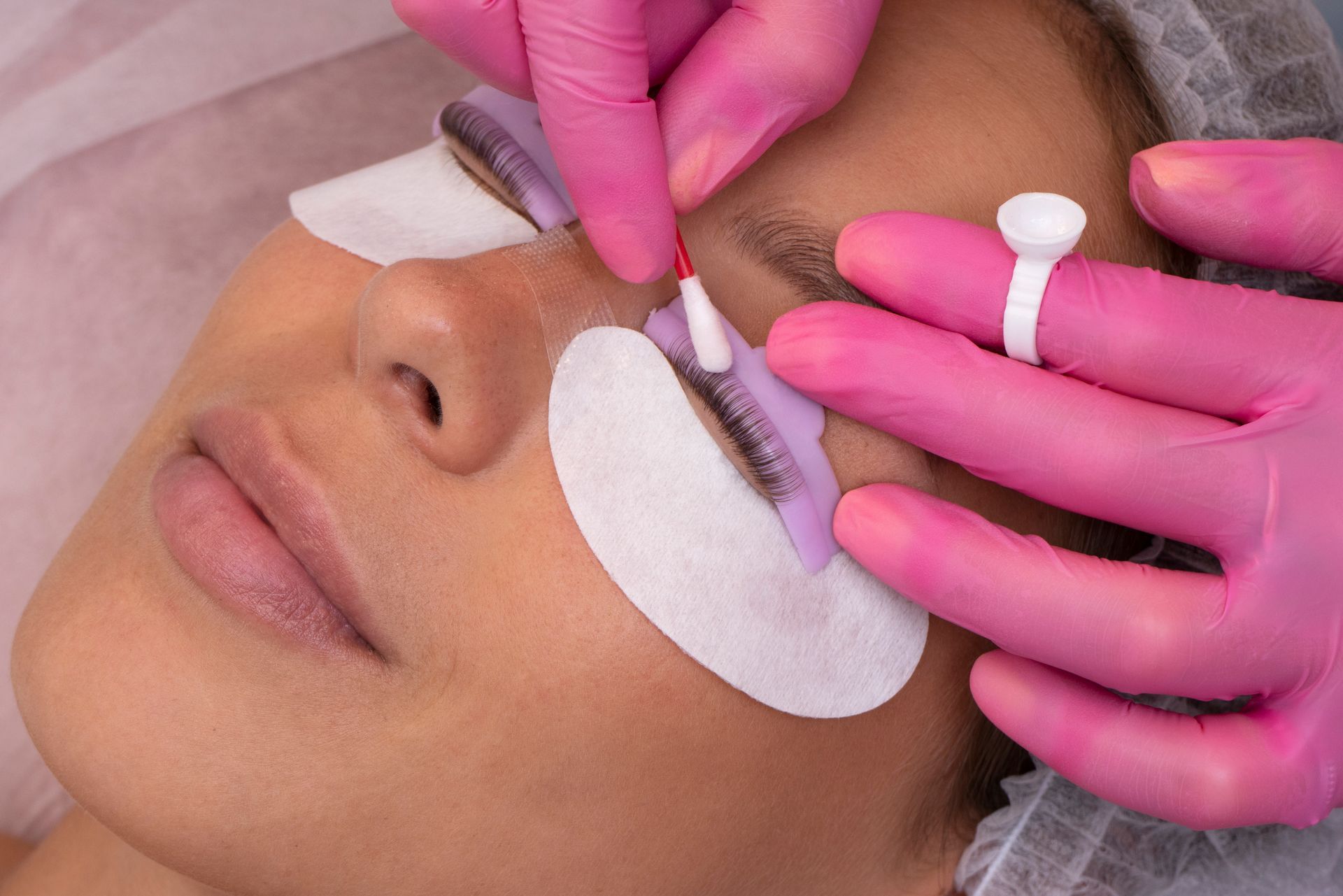 Application d'extensions de cils à une cliente avec des patchs de protection sous les yeux