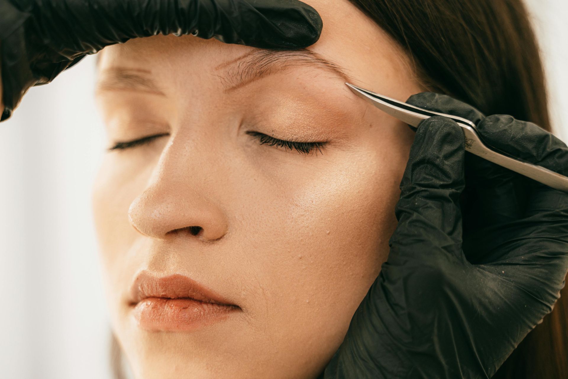 Des mains gantées appliquent du maquillage ou un soin pour les sourcils 