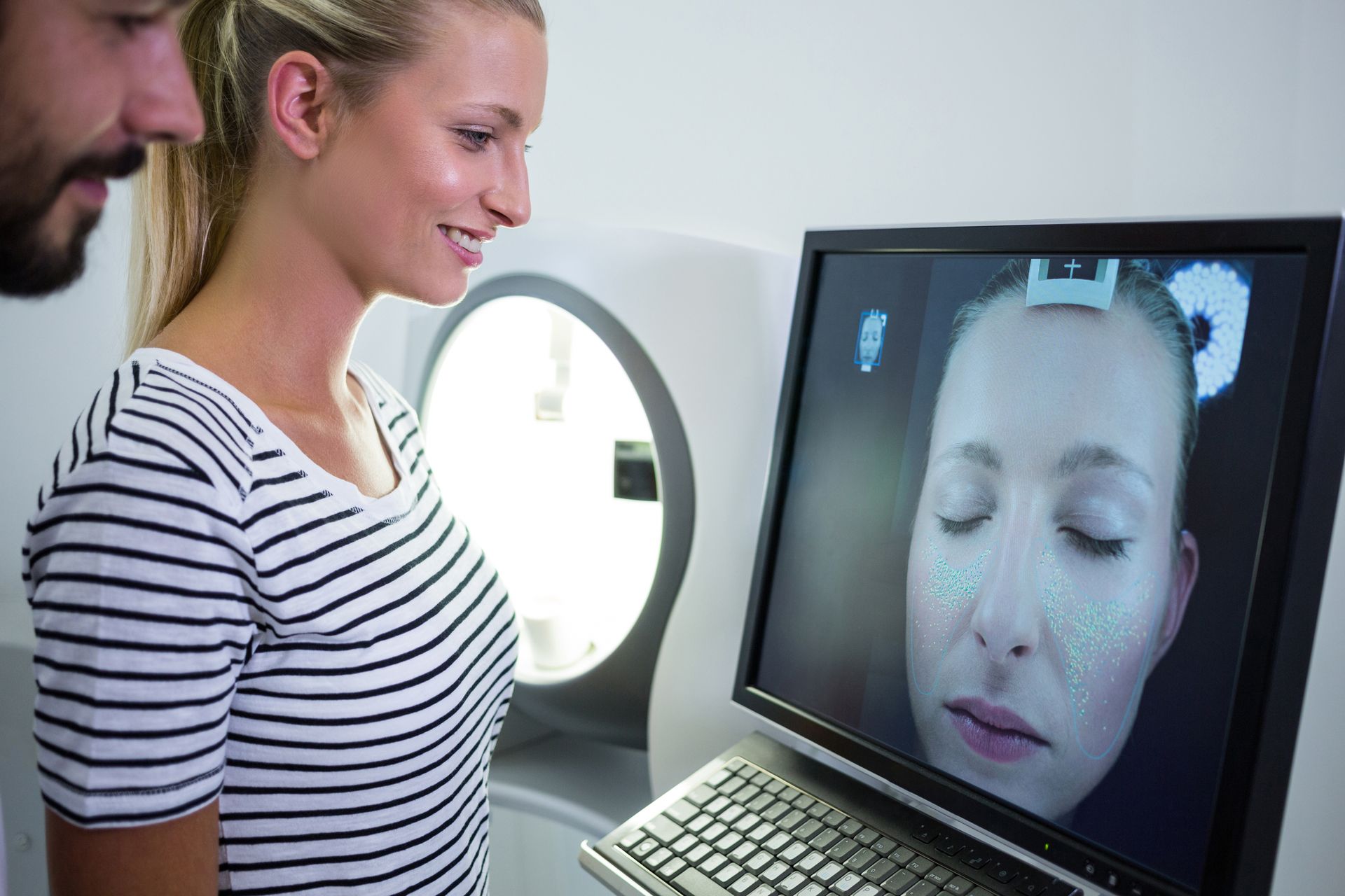 Une femme examine un scan facial sur un écran d'ordinateur 