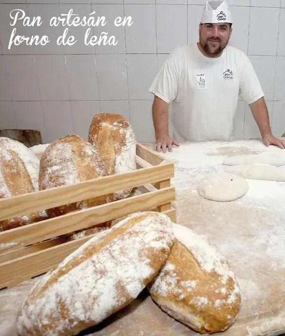 Un hombre con una camisa blanca está de pie junto a una caja de pan de madera.