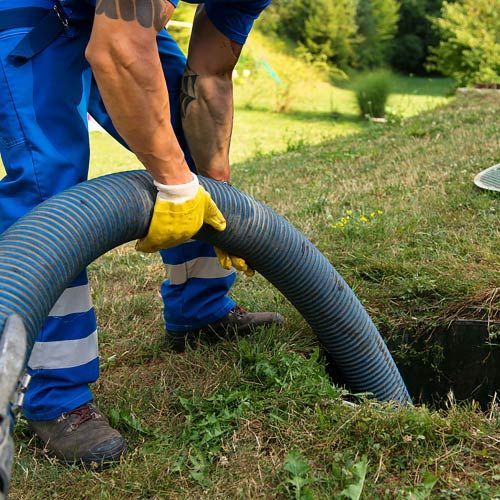 Un hombre está bombeando una manguera en un agujero en el suelo.