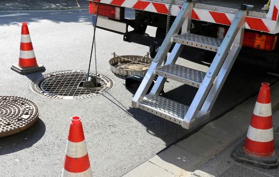 Una tapa de alcantarilla está siendo inspeccionada por un camión.