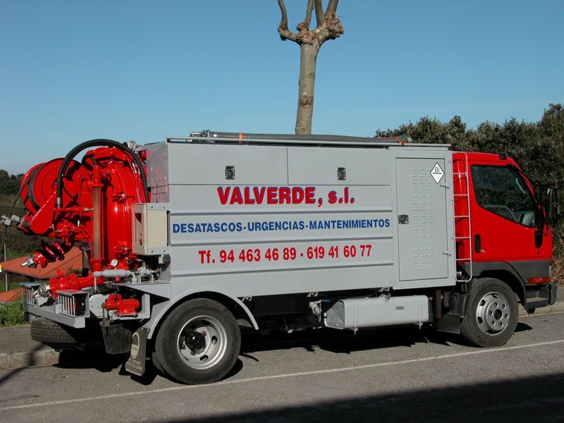 Un camión con válvulas rojas y blancas está estacionado al costado de la carretera.
