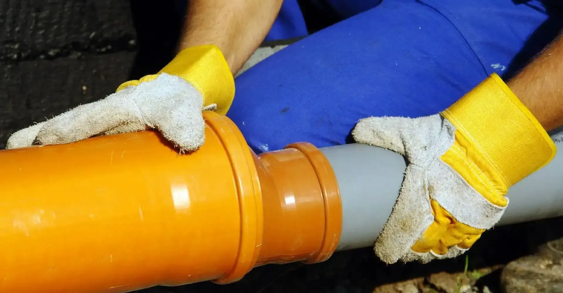 Un hombre que lleva guantes amarillos está trabajando en una tubería.