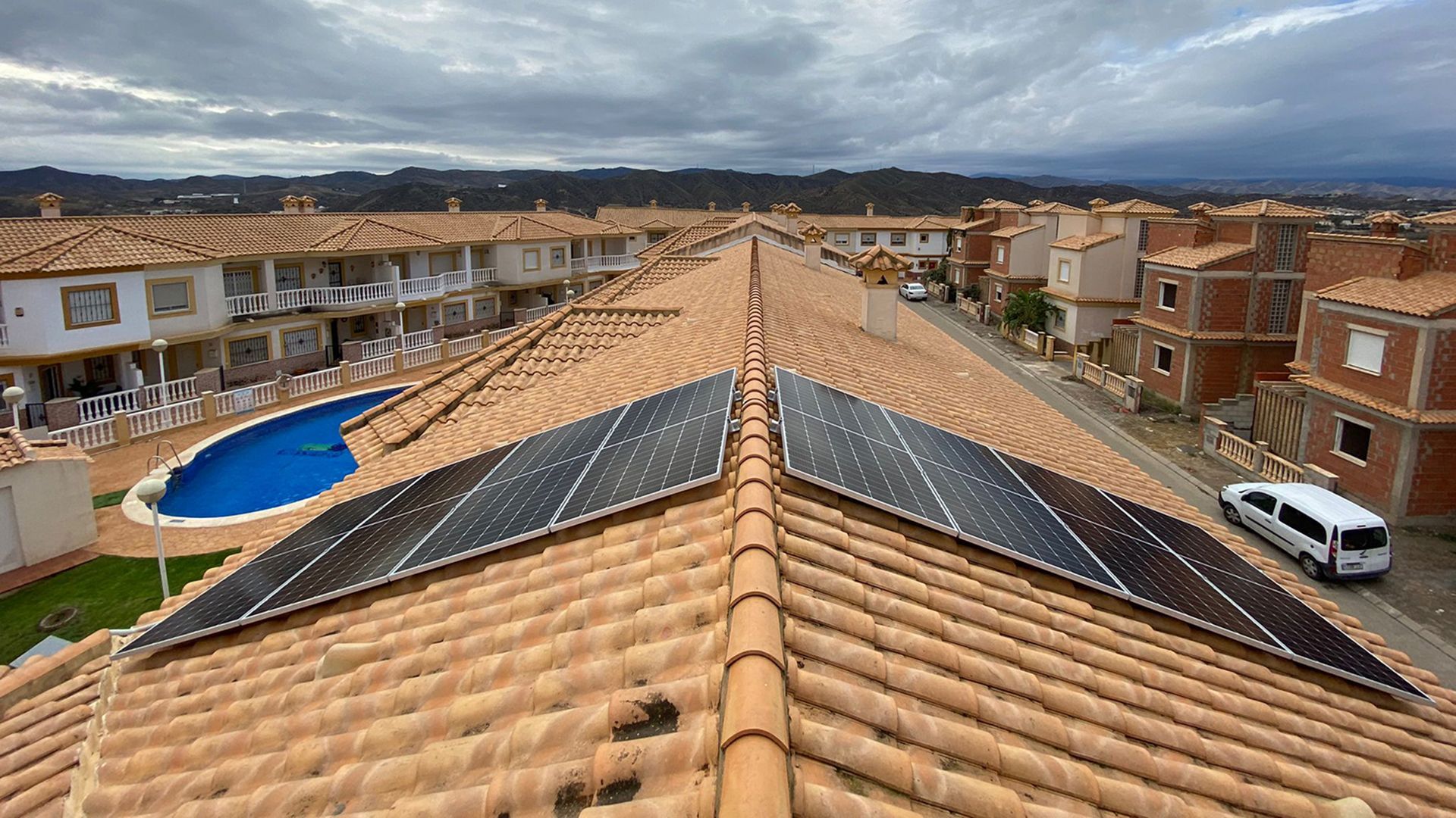 Un techo con paneles solares y una piscina al fondo.