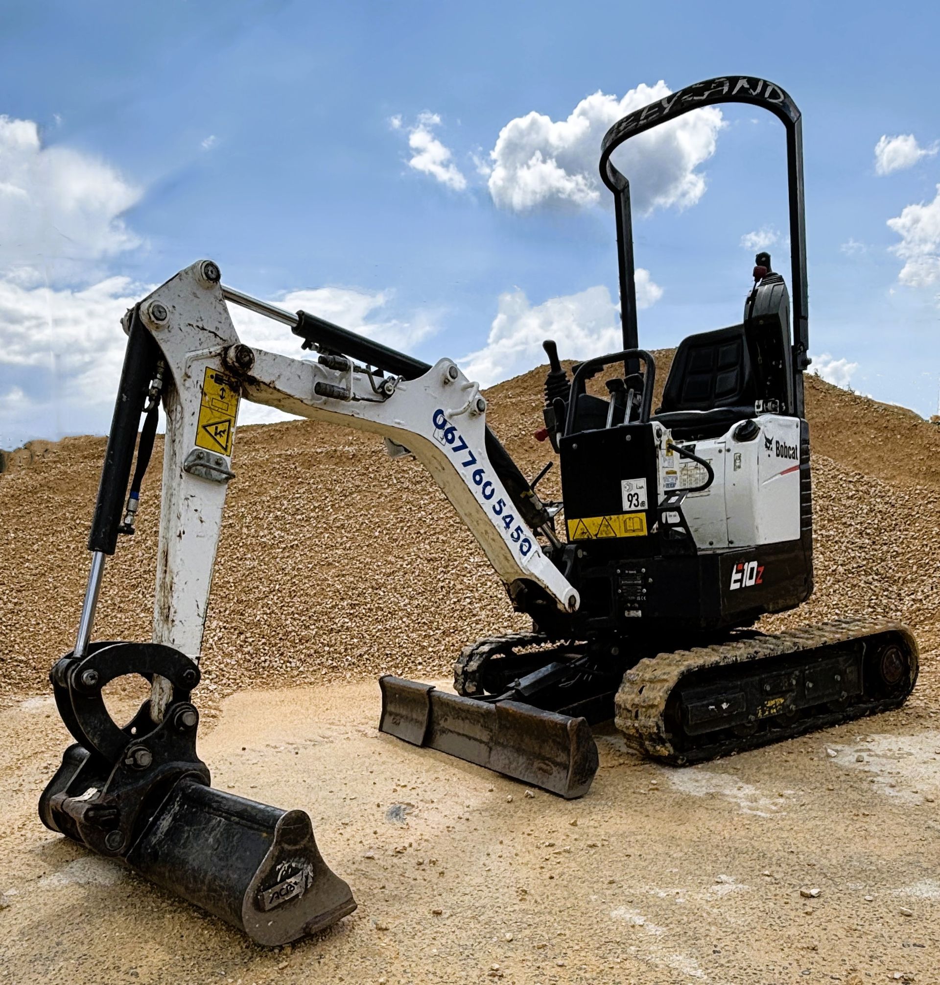 Pelleteuse blanche et noire au milieu d'un terrain de matériaux