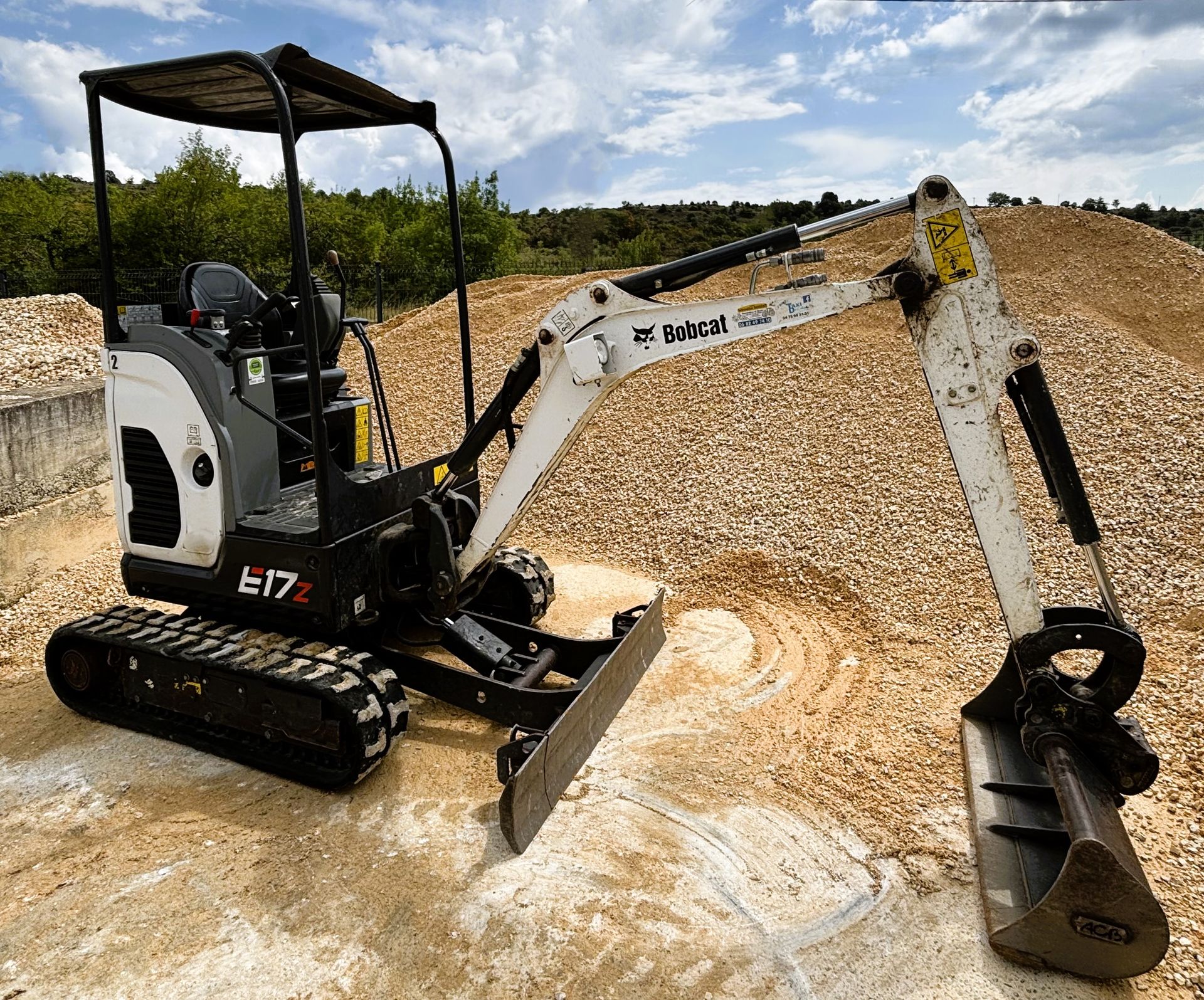 Excavatrice blanche et noire sur un terrain entouré de tas de matériaux