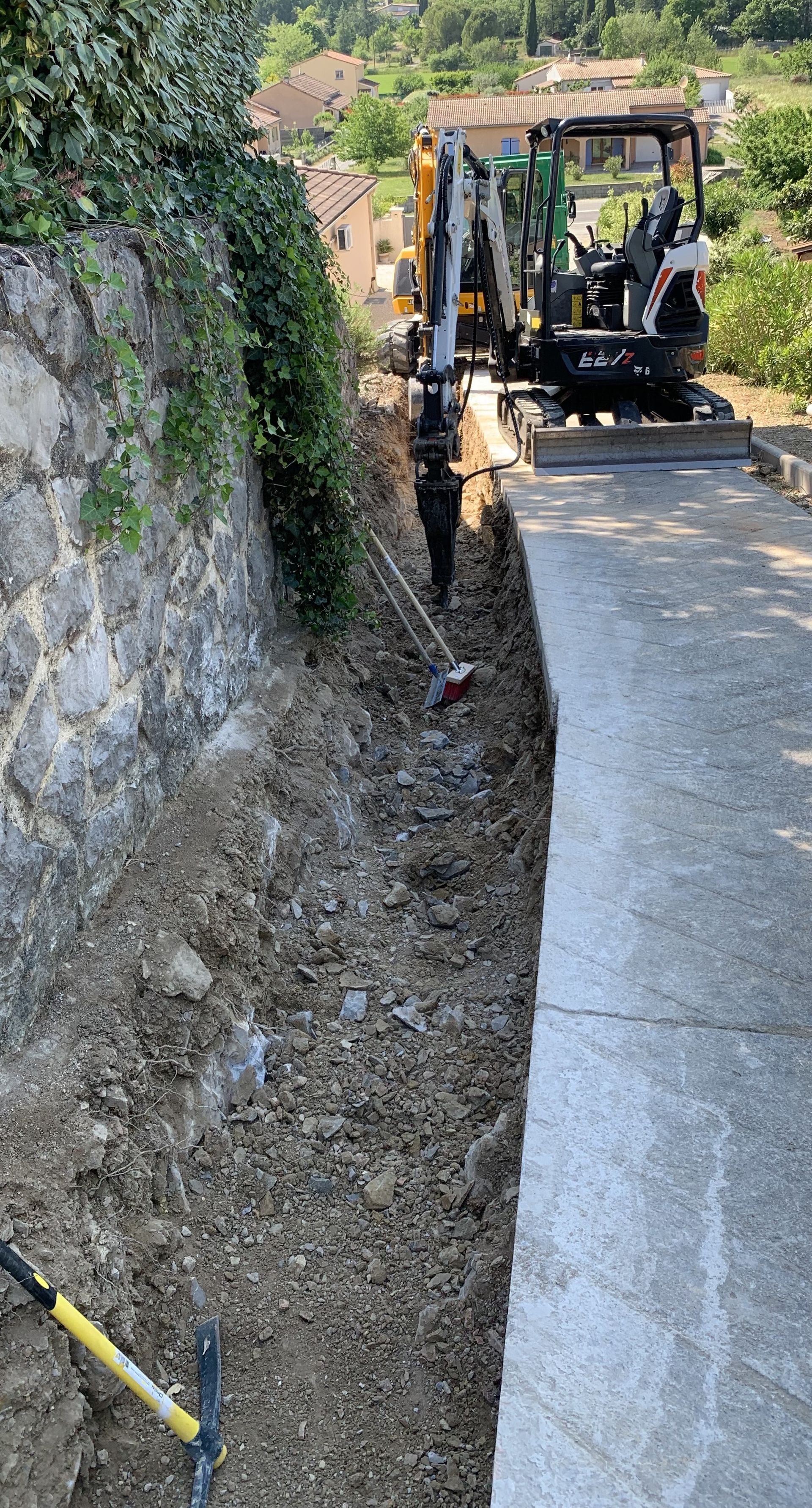 Deux mini-pelleteuses jaunes et oranges en train de creuser une voie de réseaux