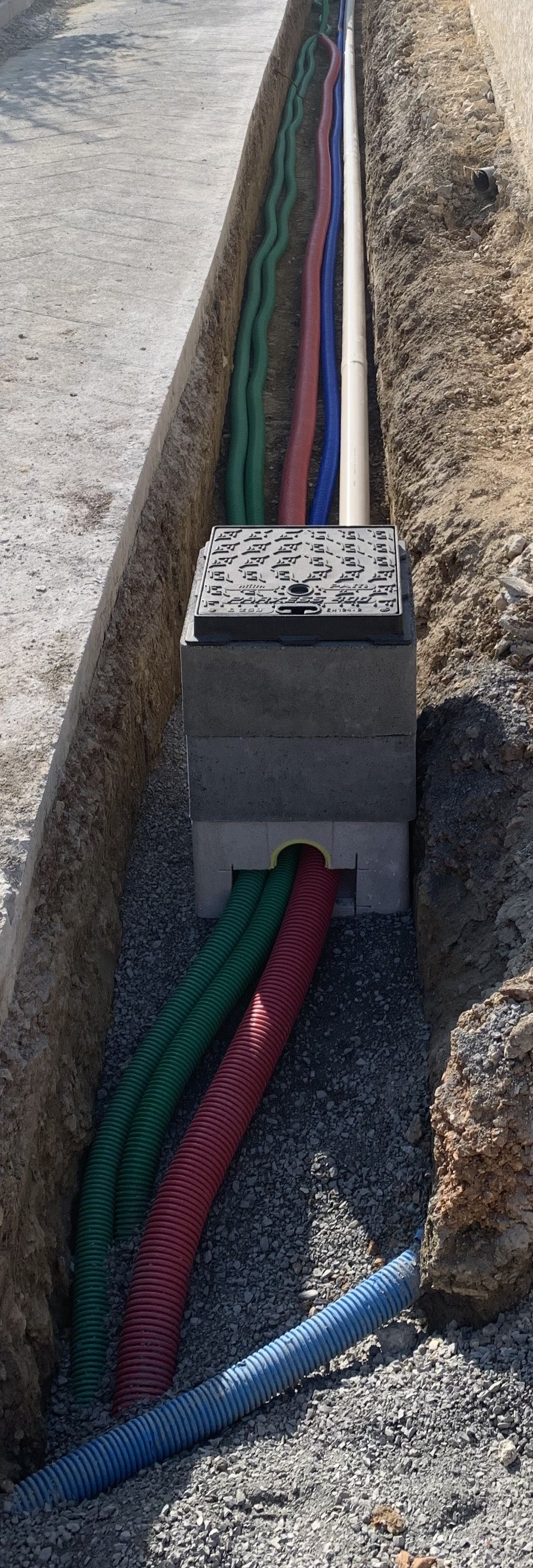Tuyaux verts, rouge, bleu et blanc dans le sol le long d'un chemin dans le sol