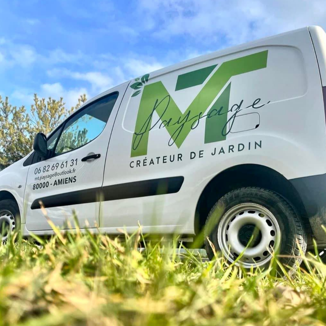 Une camionnette blanche de chantier garée sur l'herbe.