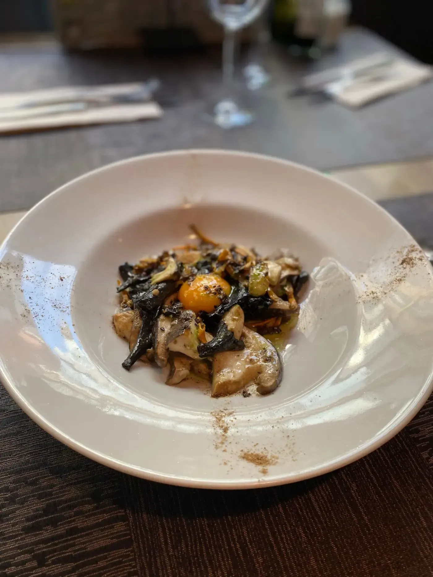 Champiñones y yema de huevo en un recipiente blanco, sobre una mesa.