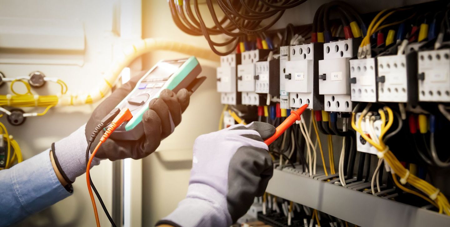 Électricien qui règle un tableau électrique avec un appareil de mesure