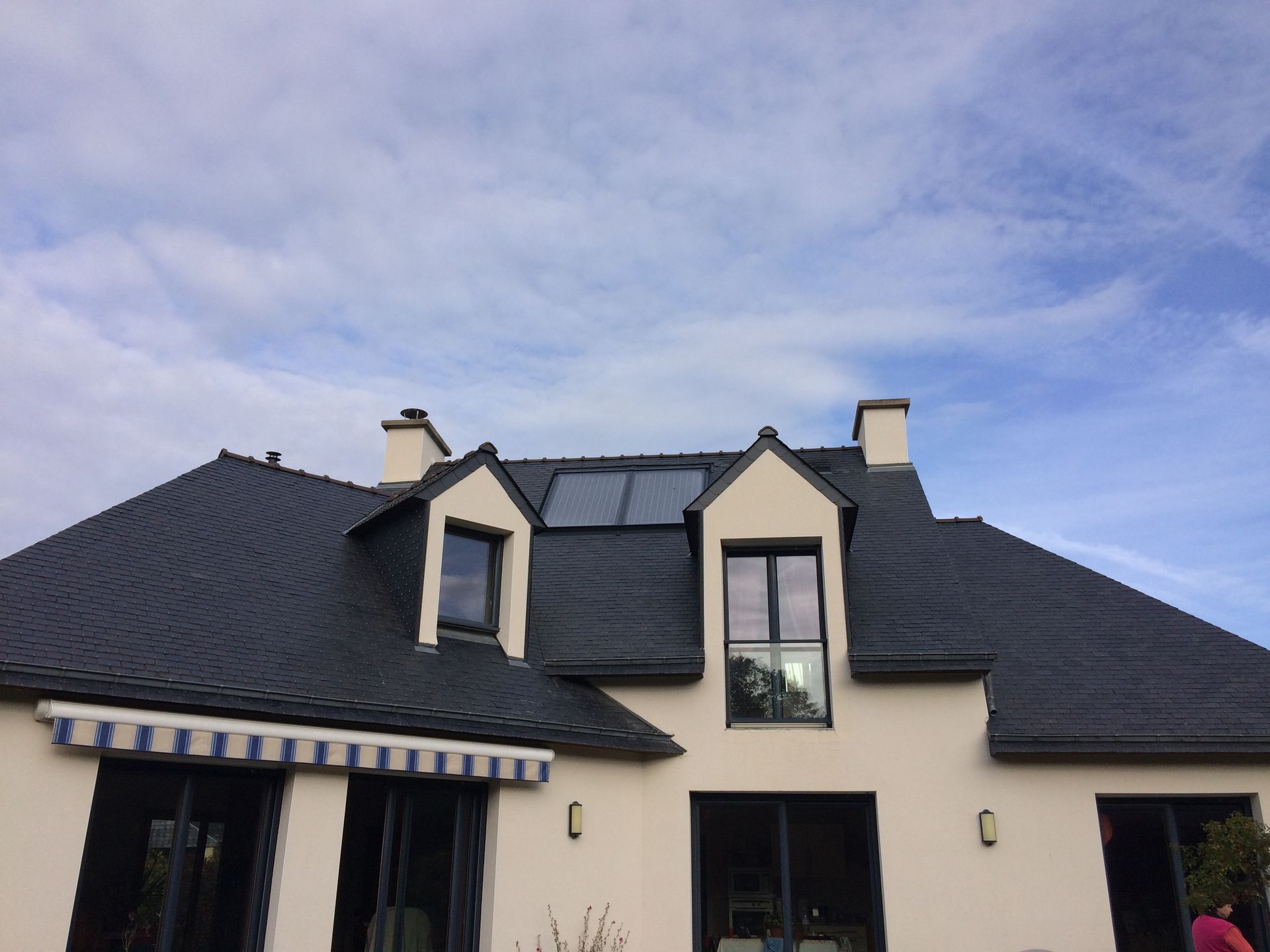 Maison blanche avec des panneaux solaires sur le toit et une pompe à chaleur à l'extérieur