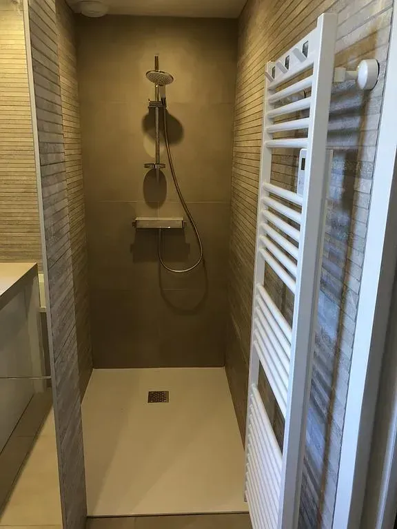 Douche à l'italienne d'une salle de bain avec un sèche serviette sur le côté
