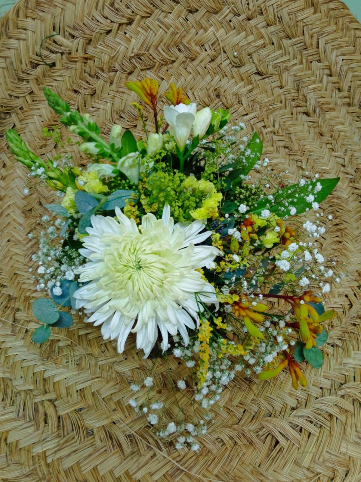 Un ramo de flores está sobre una mesa de mimbre.