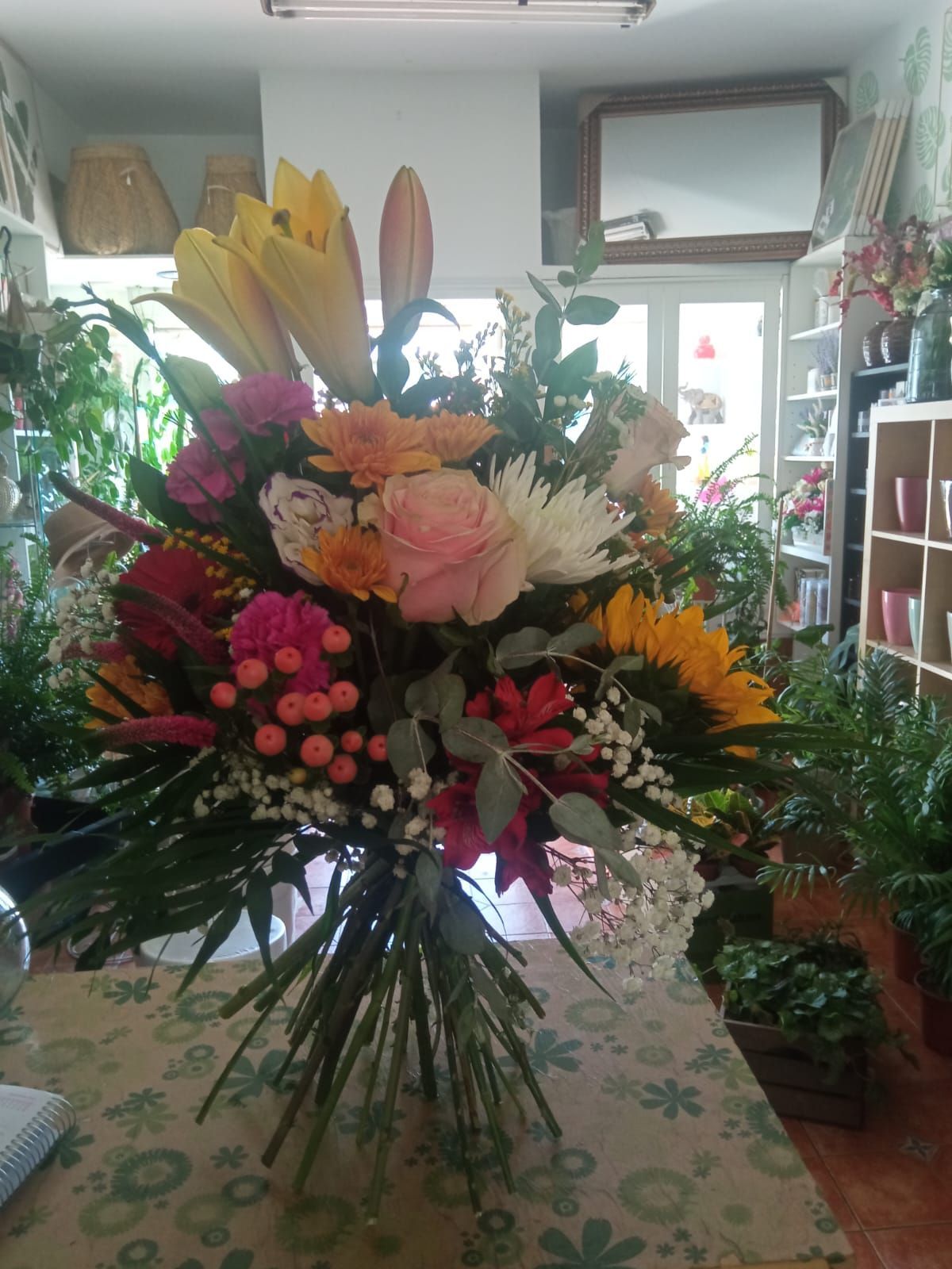 Un gran ramo de flores está sobre una mesa en una habitación.