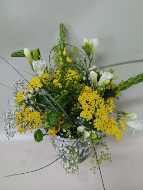 Un jarrón lleno de flores amarillas y blancas