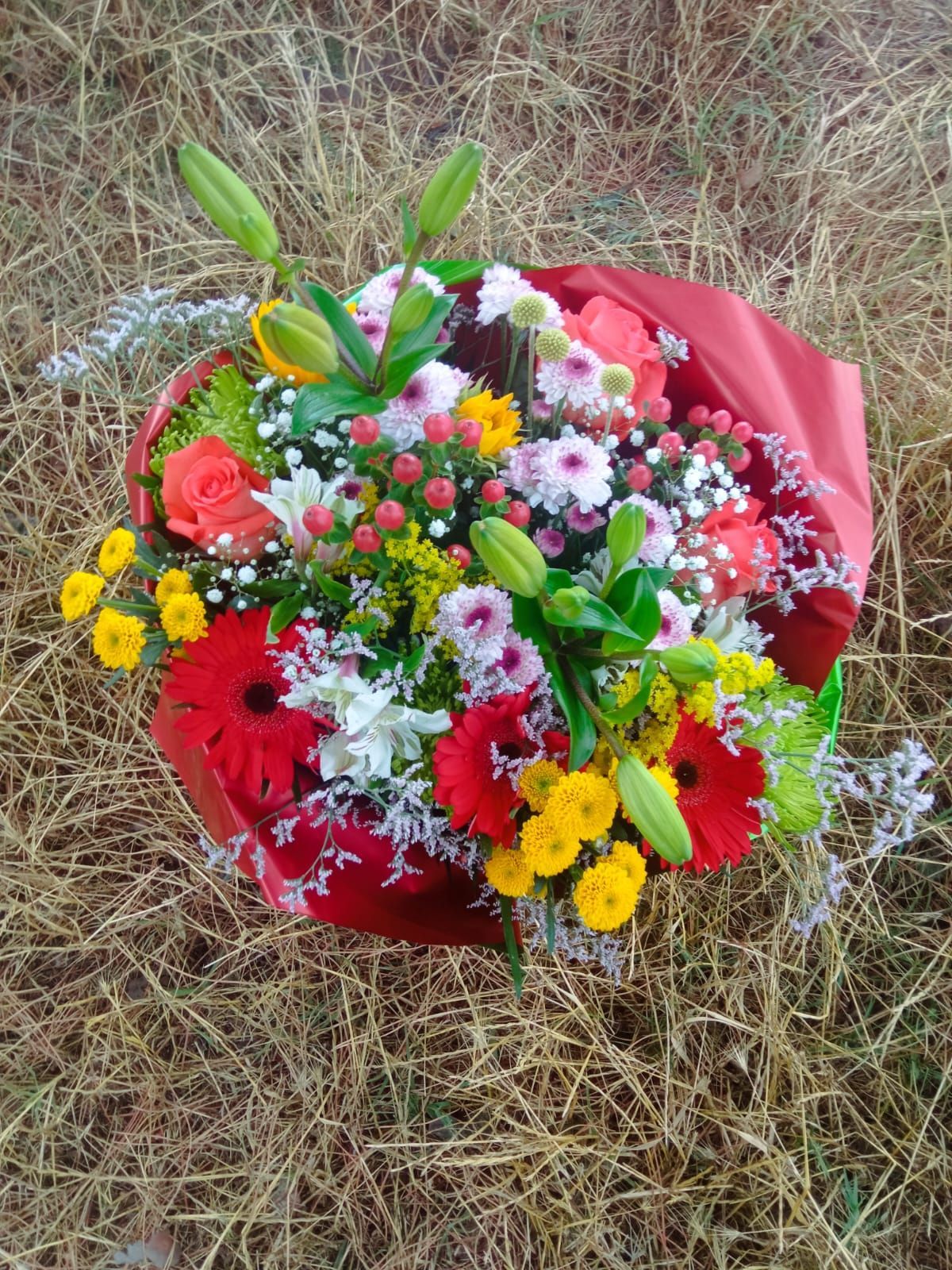 Un ramo de flores envuelto en papel rojo yace en el suelo.