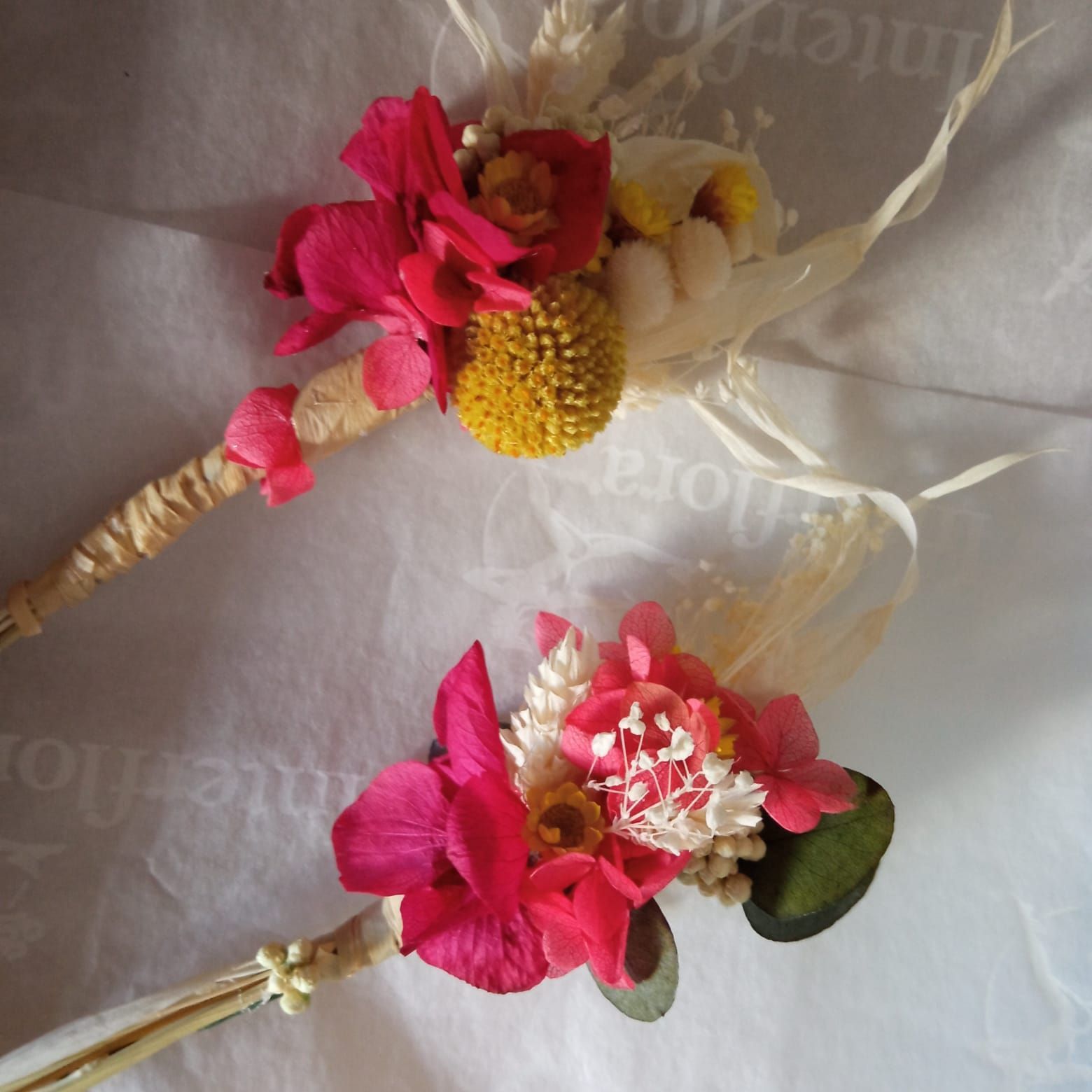Dos ramos de flores rosas y amarillas están sobre una mesa.