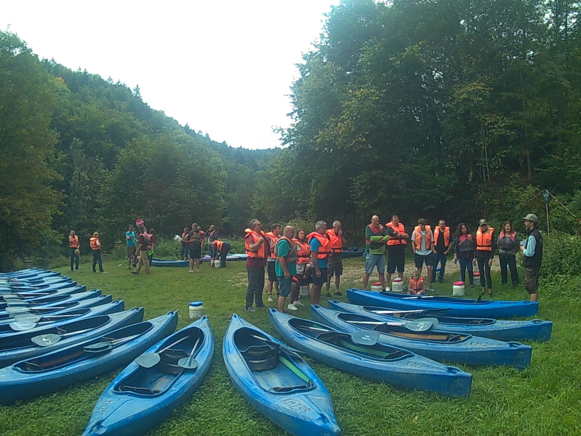 Eine Gruppe von Leuten steht um eine Reihe blauer Kajaks herum.