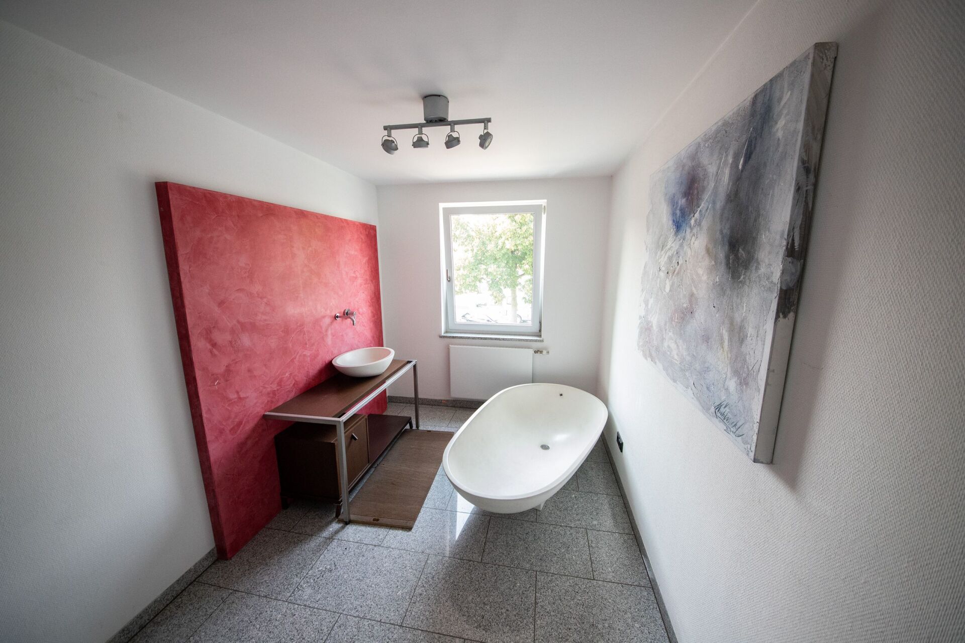 Ein Badezimmer mit Badewanne, Waschbecken und Gemälde an der Wand.