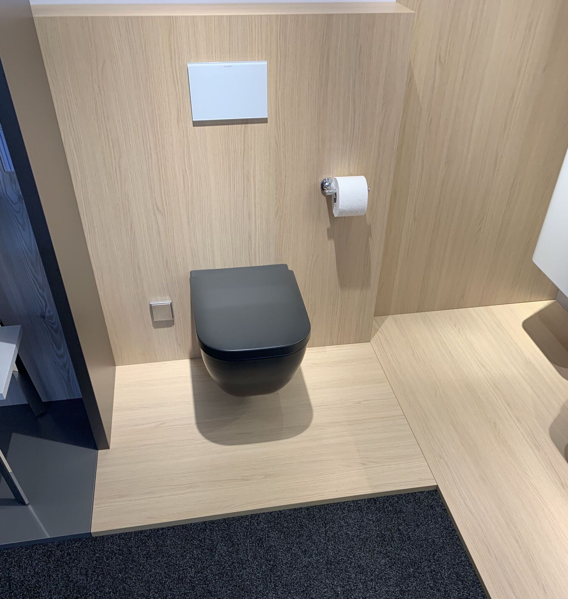 Ein Badezimmer mit Toilette und Papierhandtuchhalter