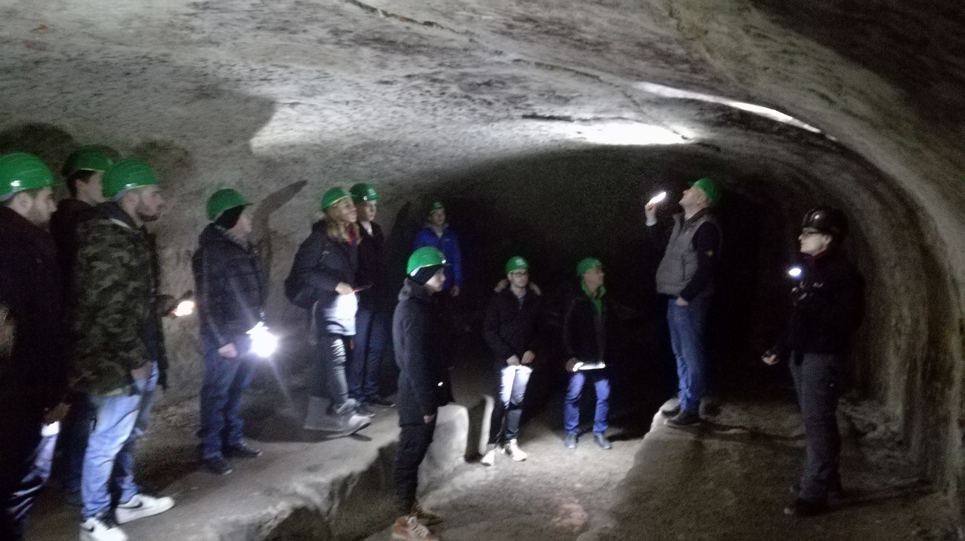 Eine Gruppe von Menschen mit Schutzhelmen steht in einer Höhle.