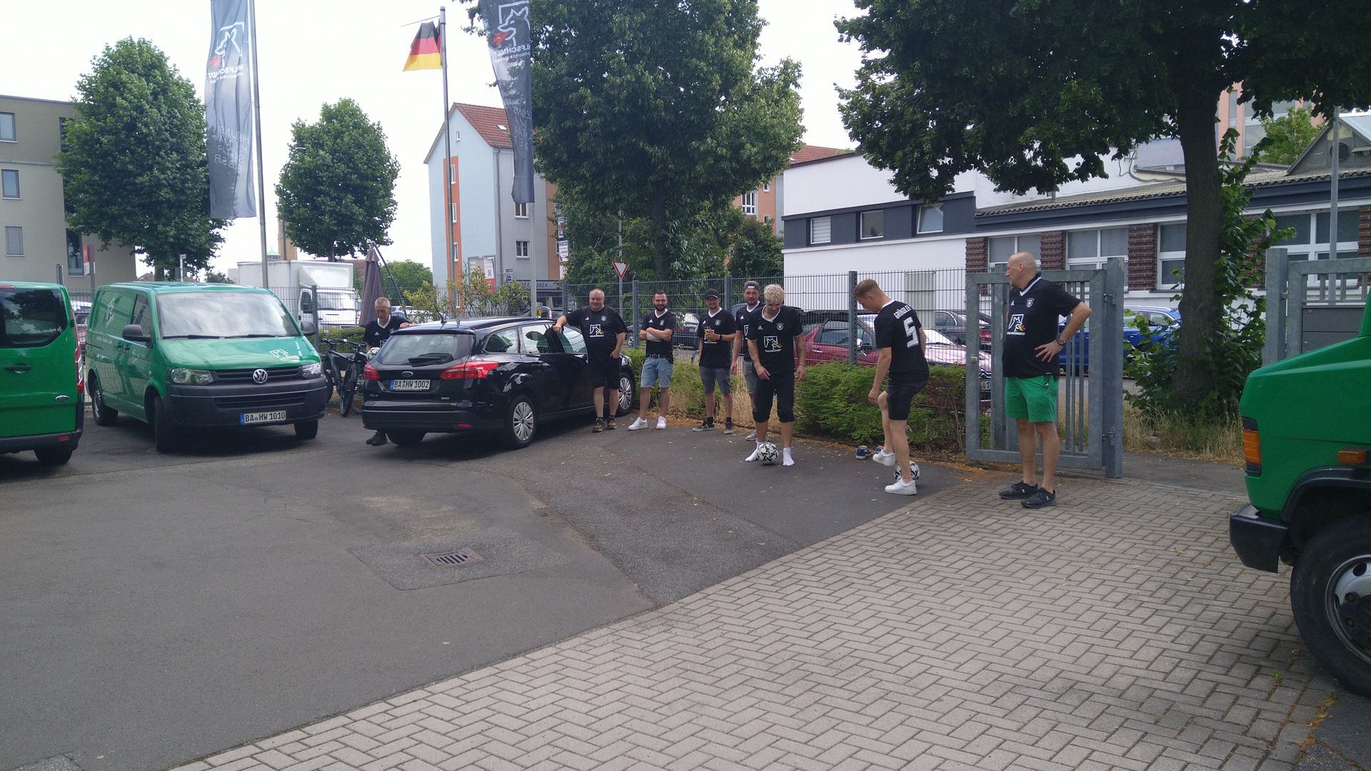 Eine Gruppe von Menschen steht auf einem Bürgersteig neben einem grünen Lieferwagen