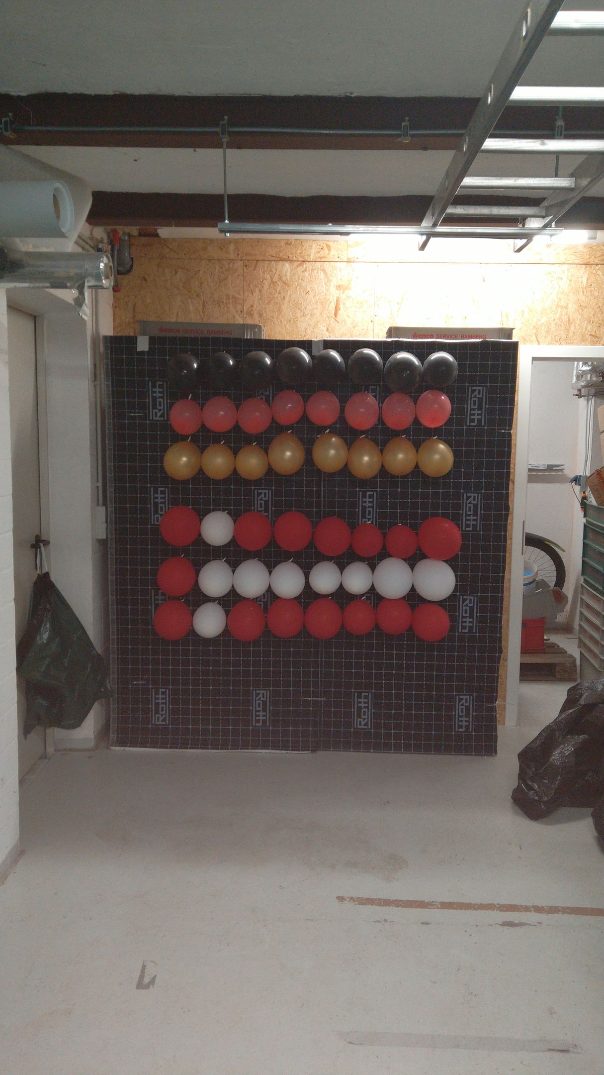 In einem Zimmer hängt ein Haufen Luftballons an der Wand.