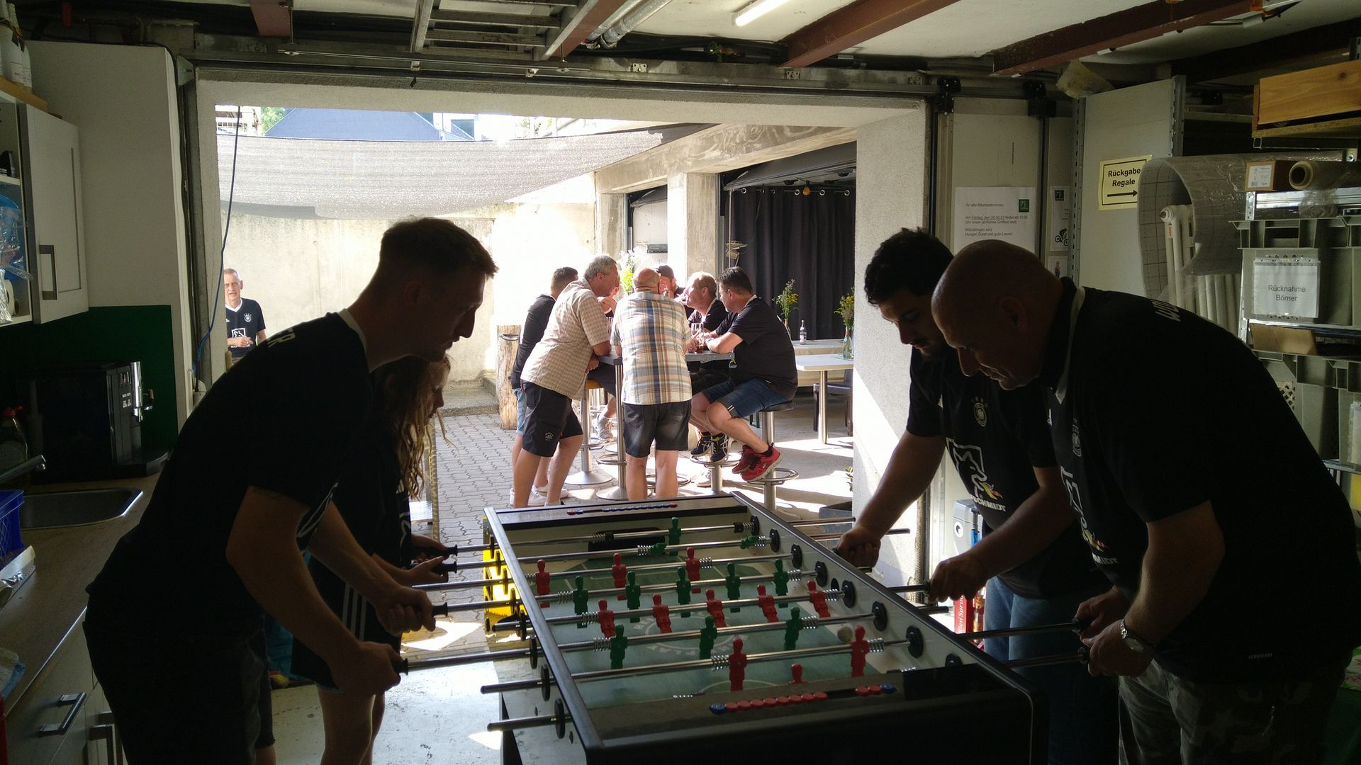 Eine Gruppe Männer spielt in einer Garage Tischfußball.