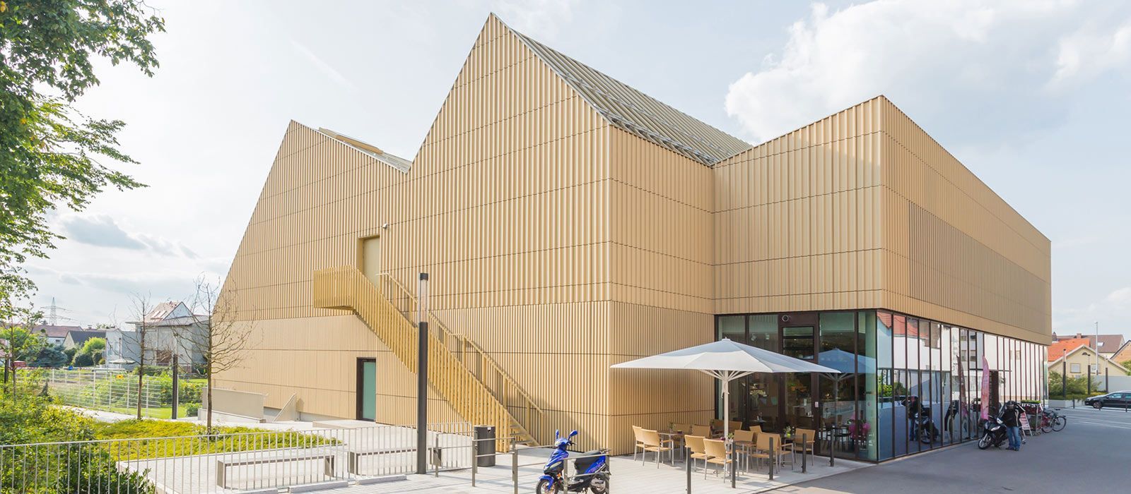 Ein großes Holzgebäude mit einer Treppe und Sonnenschirmen davor.