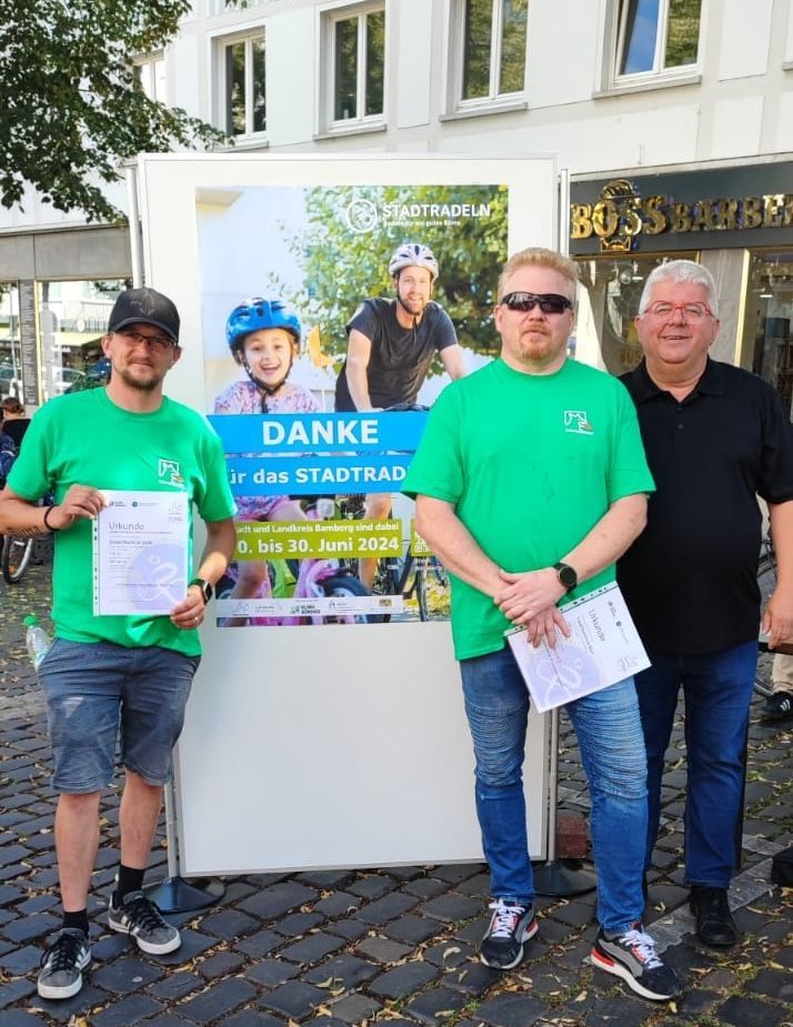 Drei Männer stehen vor einem Schild mit der Aufschrift „Danke“
