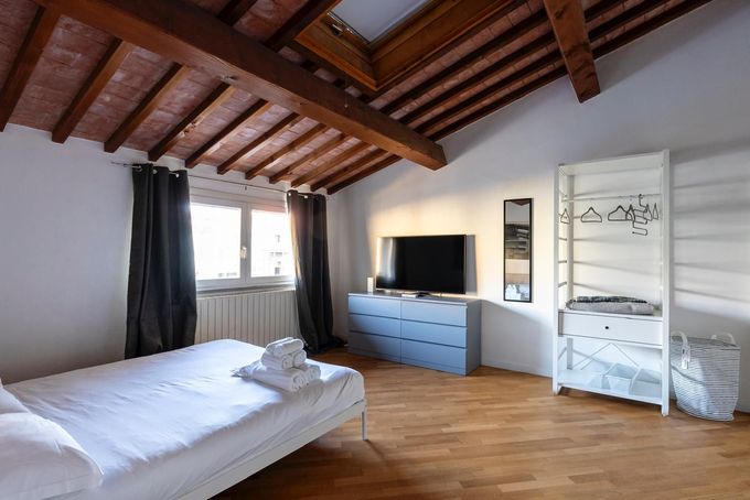 A bedroom with a bed and a television on the wall