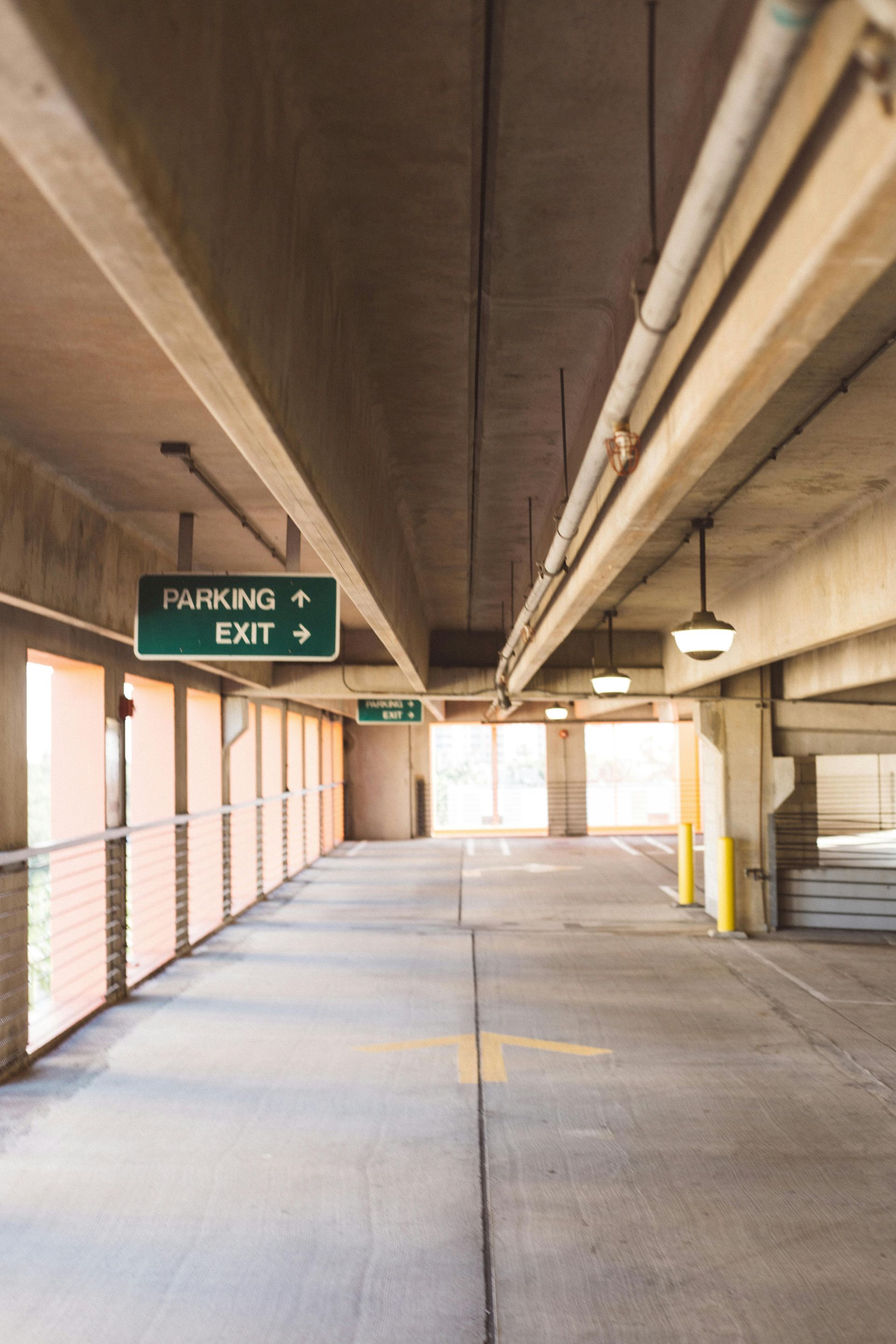 An empty parking garage with pink columns and yellow markings.