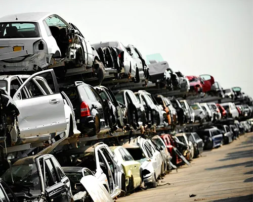 Un montón de coches están apilados uno encima del otro en un depósito de chatarra.