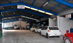 Una fila de coches están aparcados en un garaje bajo un techo azul.