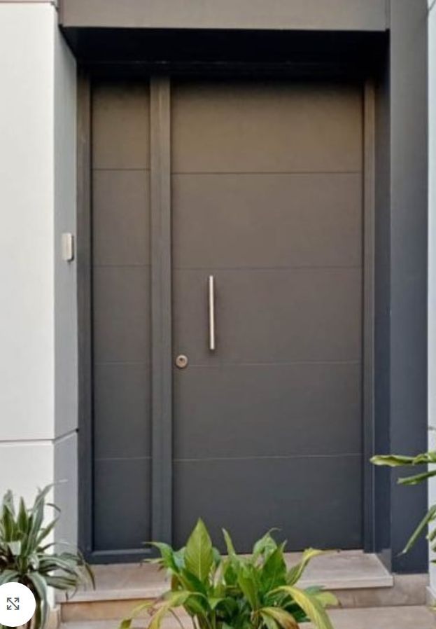 Una puerta gris con una valla al fondo.