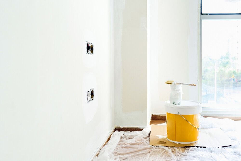 Un balde de pintura está en el suelo en una habitación vacía.